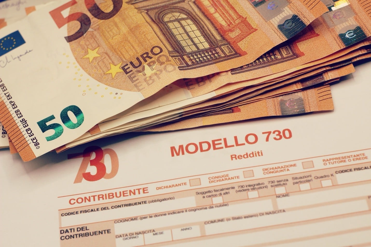Euro banknotes on Italian tax form Modello 730 illustrating financial income requirements for the Italy Elective Residence Visa
